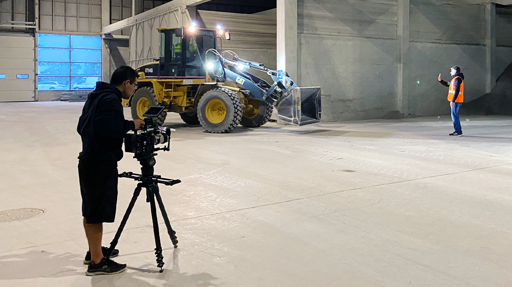 A filmmaker shooting in a large, empty warehouse