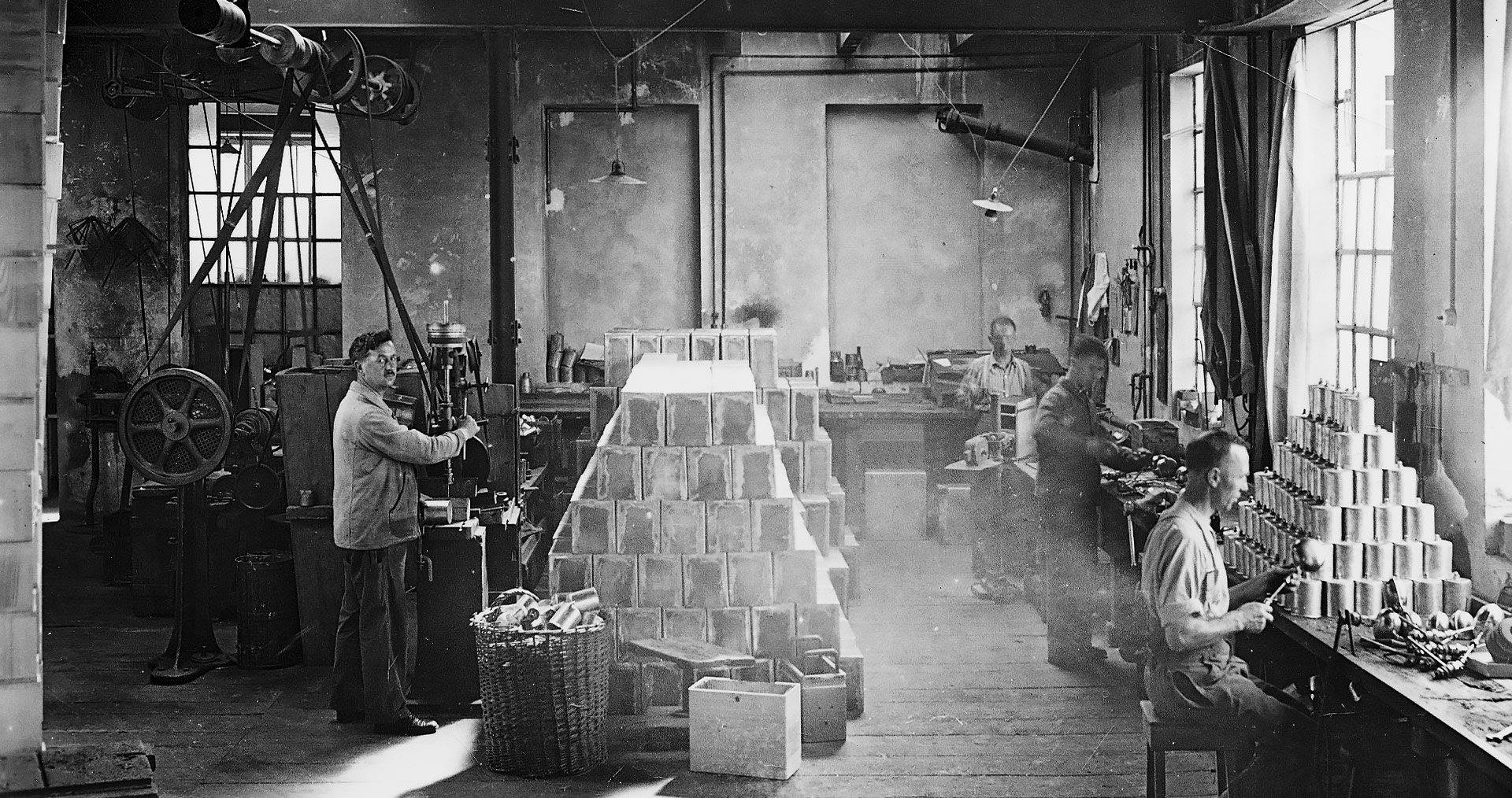 Historical black and white photo of a factory floor with workers