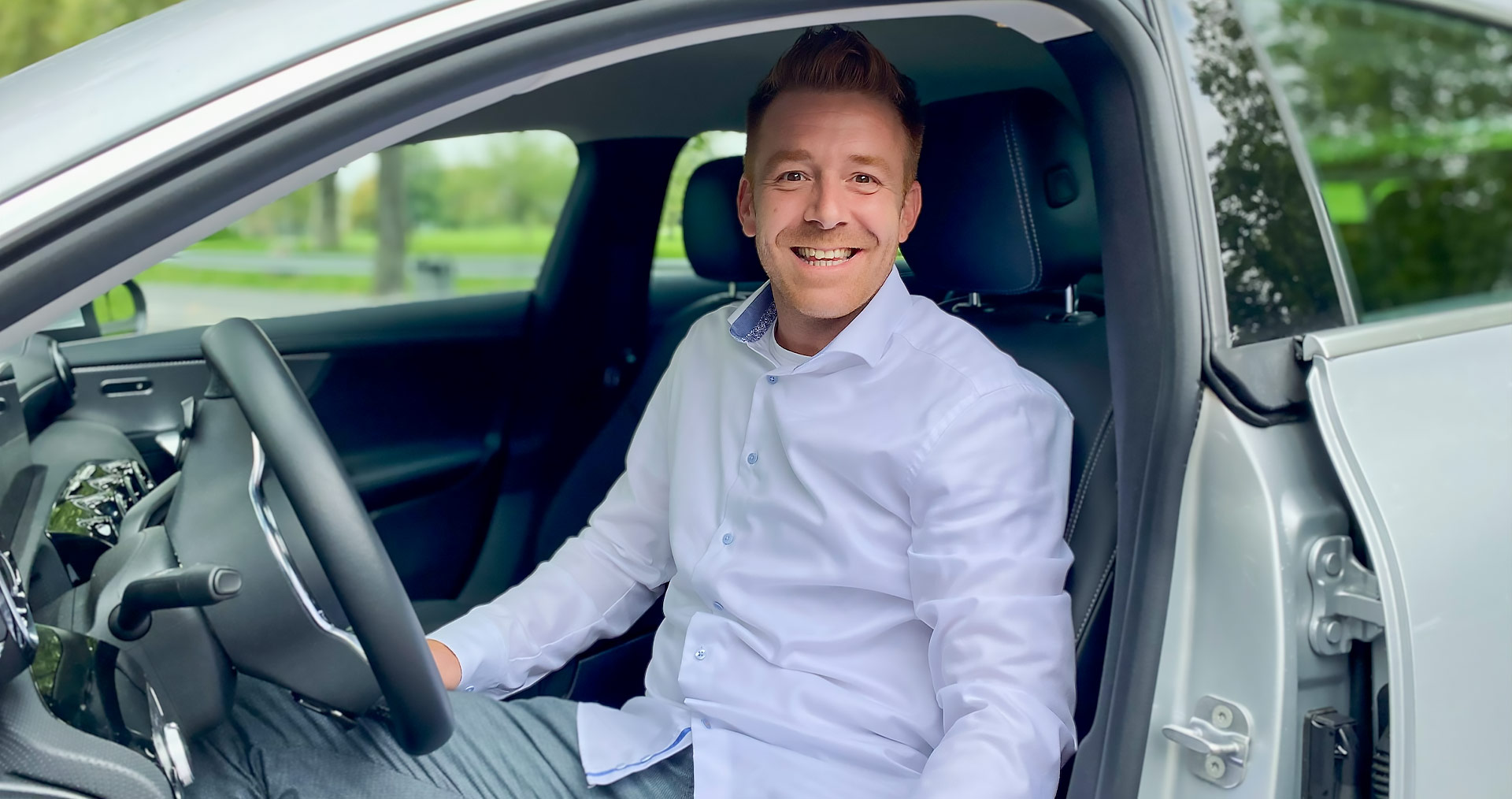 Benjamin Keller, sales consultant at Geberit, smiling in his car on the way to clients