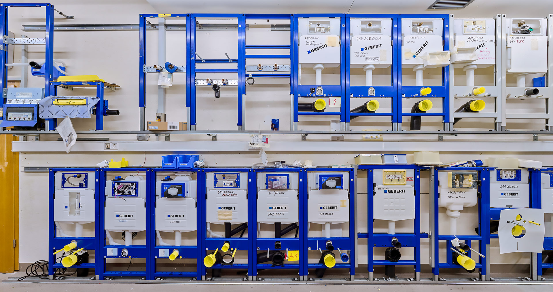 Storage rack with various models and spare parts of Geberit flush tanks, demonstrating the long-term availability of spare parts