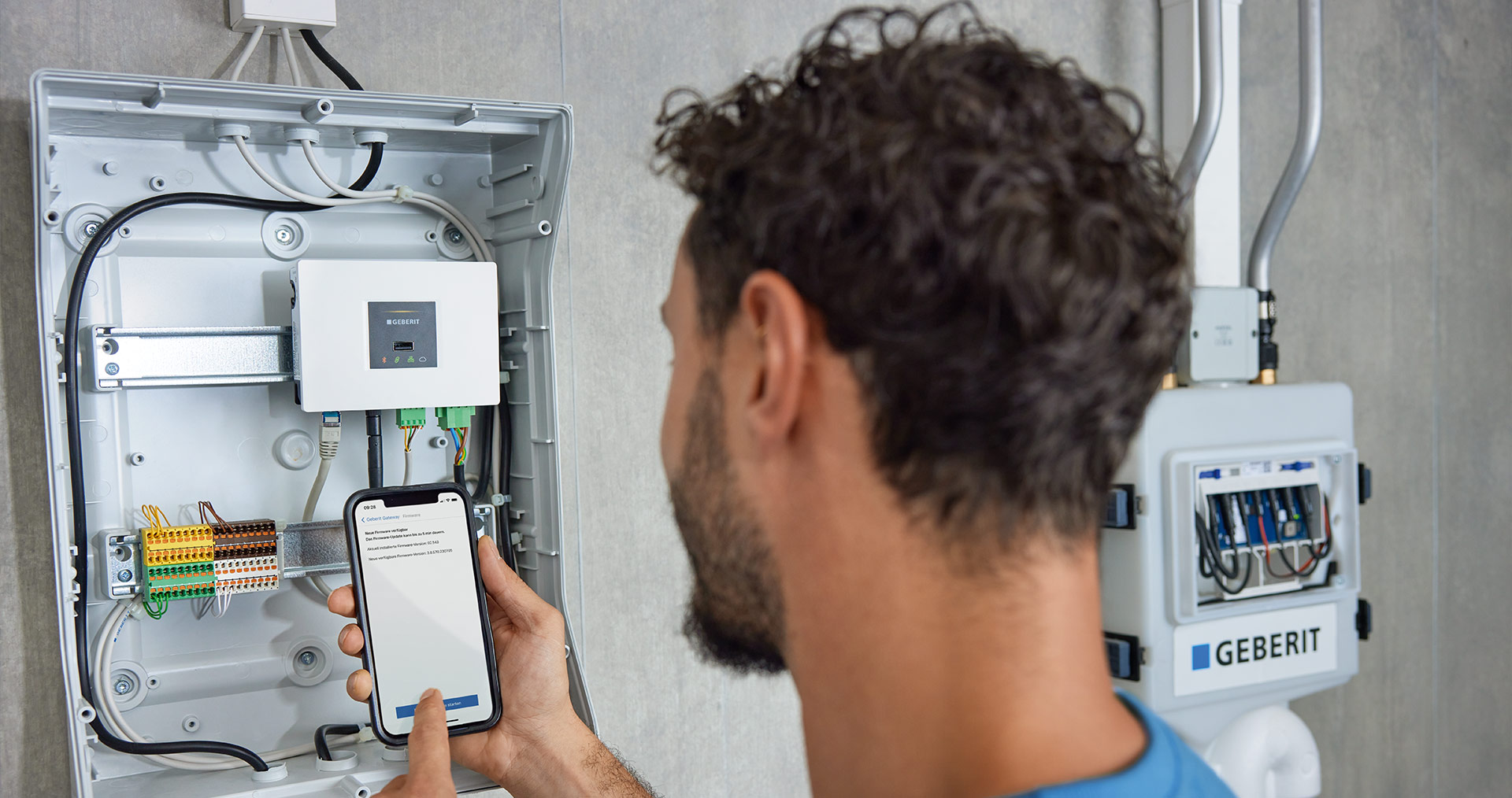 Technician using a smartphone to control and monitor plumbing devices with Geberit Connect technology in a modern bathroom