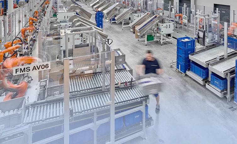 Modern factory hall with robots and workers carrying out production and logistics processes