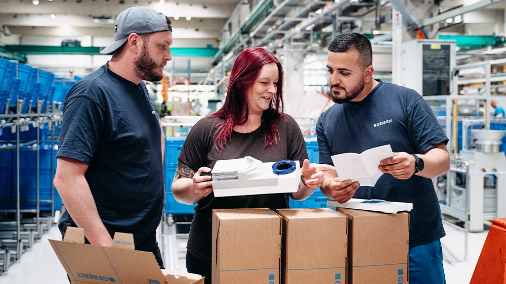 Teamwork at Geberit: Sarah Berner discussing with colleagues in the factory