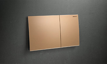 Flush plate for WC flush from Geberit, model Sigma70, in frameless design and bronze colour, apparently floating mounted on a dark background