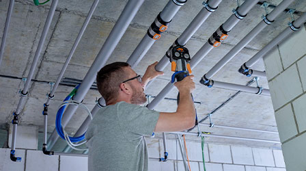 Worker installing the Geberit FlowFit pipe system, simplifies the installation process