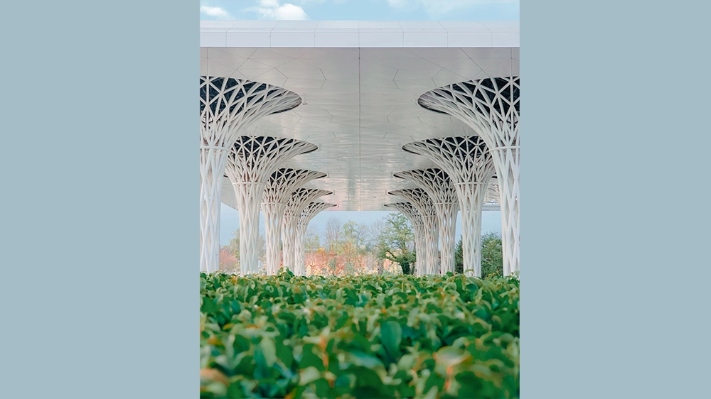 The railway station has a green roof and green spaces surrounding it.