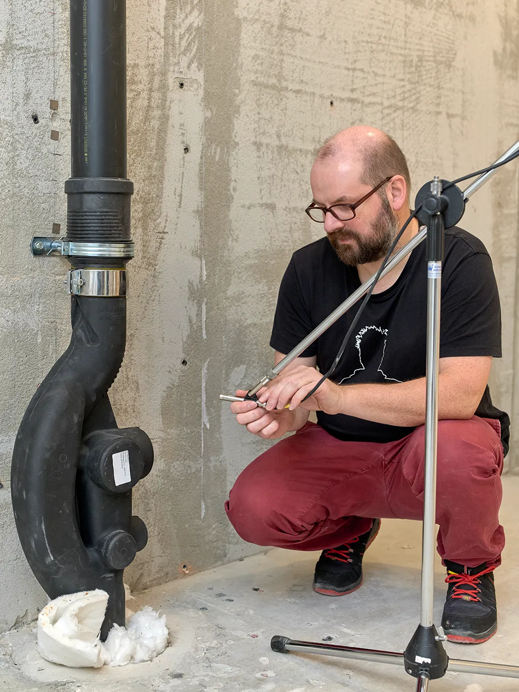 A man wearing glasses kneeling and preparing a measurement in the Technology and Acoustics Laboratory in Rapperswil-Jona (CH).