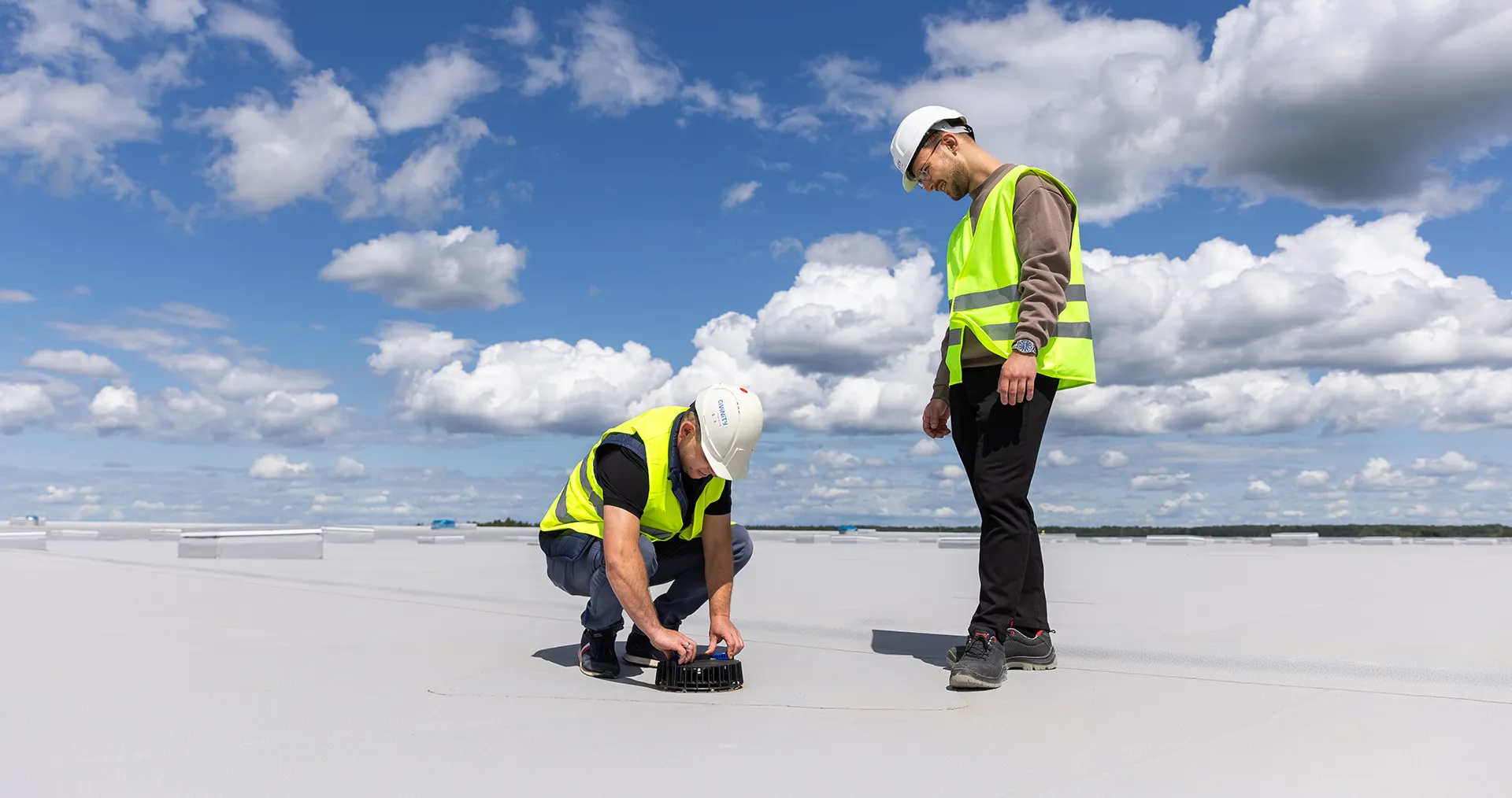Installing of the roof drainage system by two workers wearing yellow vests.&nbsp; (Photo)