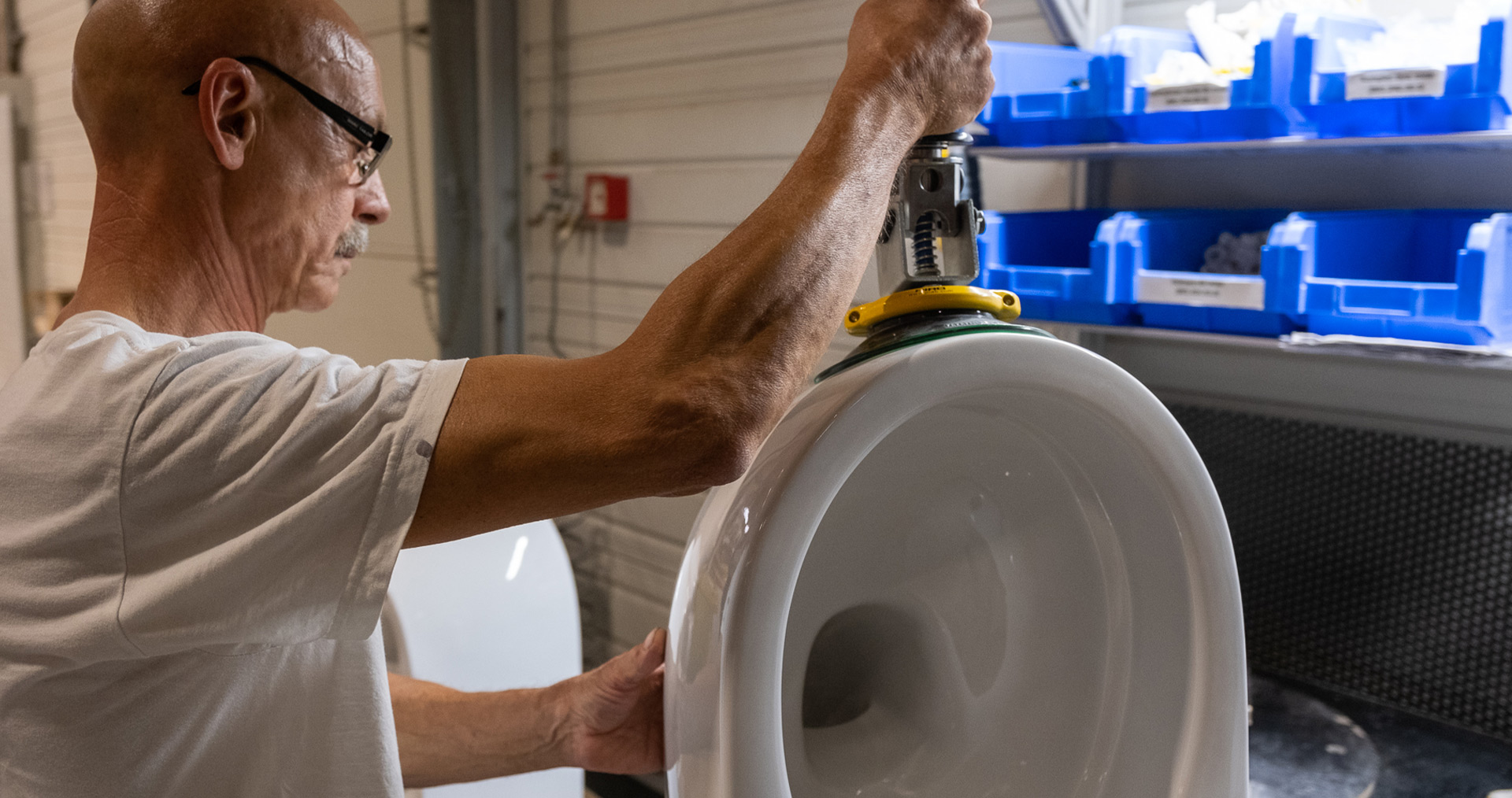 Ein Mitarbeiter hebt ein Keramik-WC mit Hilfe der Hebehilfen
