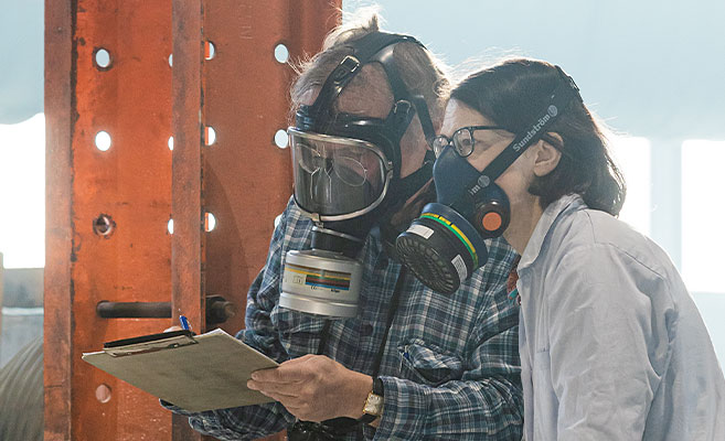Stephanie Köble und ein Mann mit Schutzmasken bei der Brandschutzprüfung 