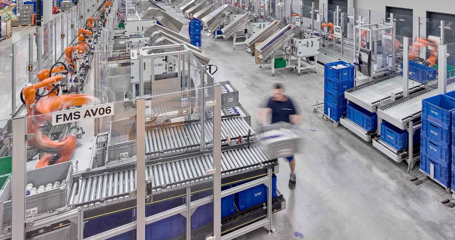 Moderne Fabrikhalle mit Robotern und Arbeitern, die Produktions- und Logistikprozesse durchführen