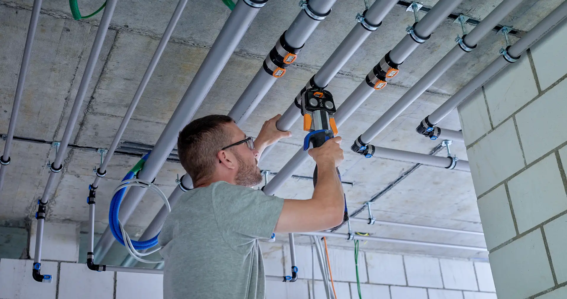 Handwerker bei der Installation von Geberit FlowFit Rohrsystem, vereinfacht den Installationsprozess