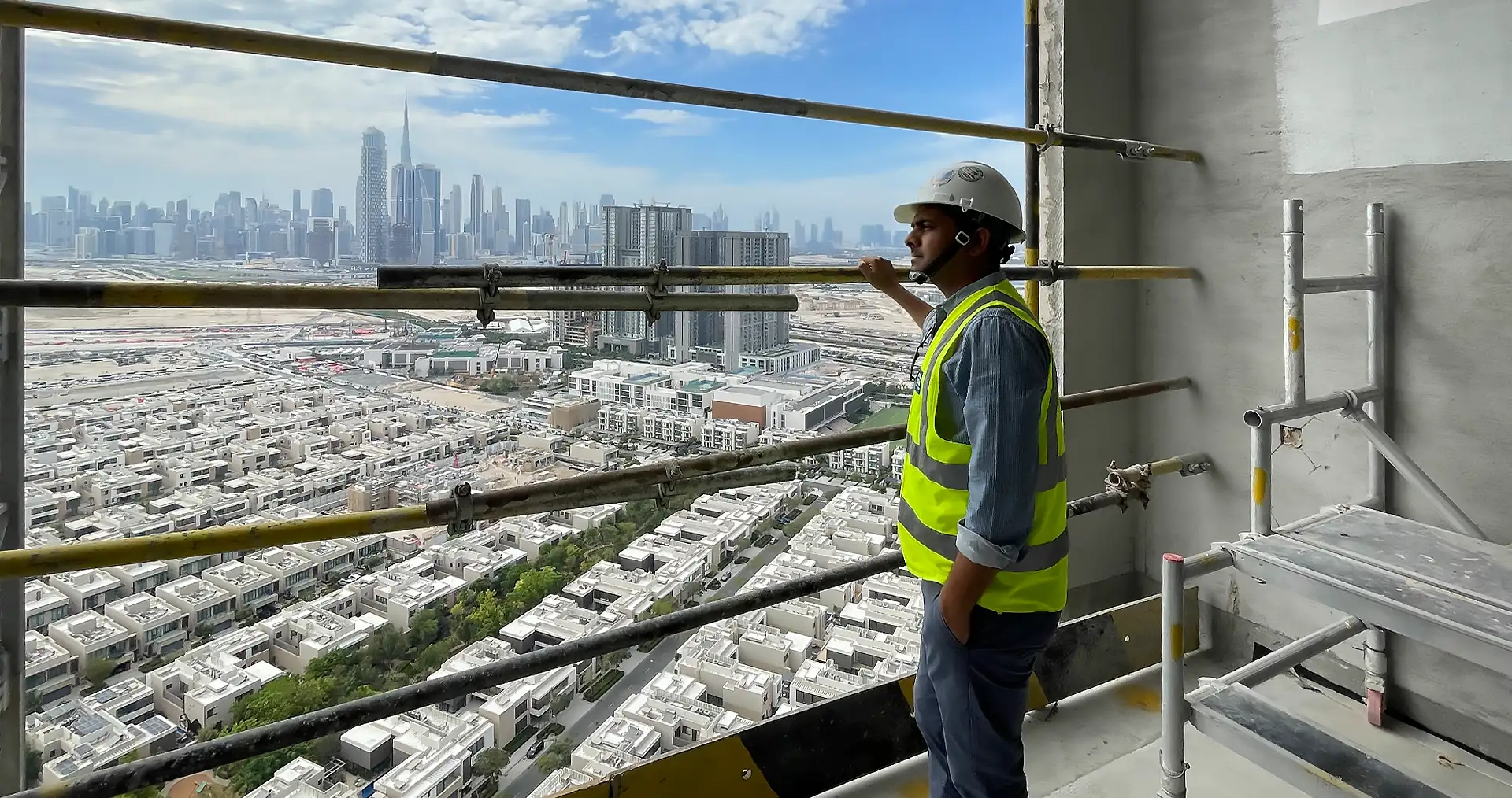 Arbeiter namens Vineet Kumar Bhaskar auf einem Hochhausgerüst mit Stadtblick