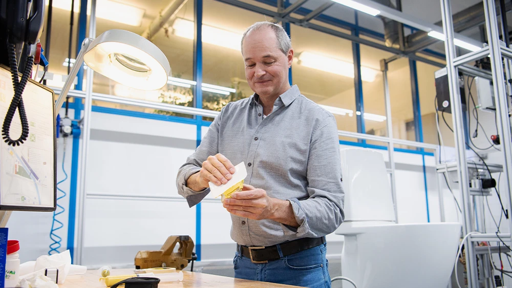 Markus Ott, Projektleiter im Sanitärlabor trägt die Paste auf die Lochplatte auf