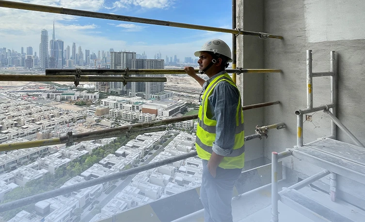 Arbeiter namens Vineet Kumar Bhaskar auf einem Hochhausgerüst mit Stadtblick