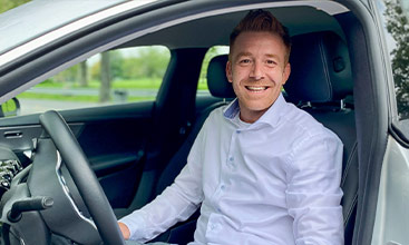 Benjamin Keller, Verkaufsberater bei Geberit, lächelt im Auto auf dem Weg zu Kunden