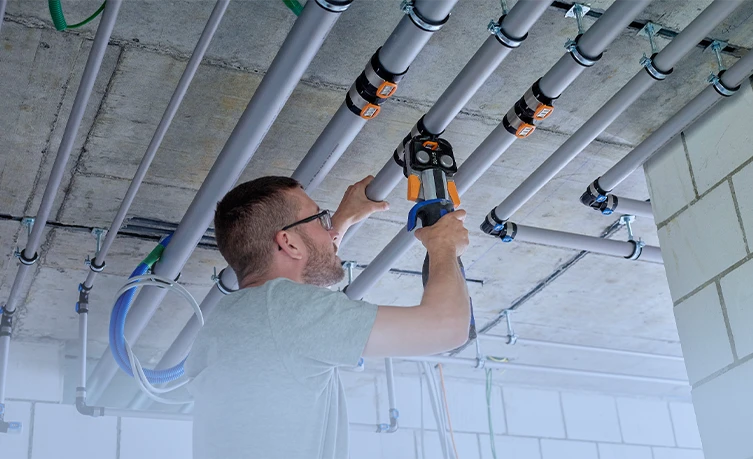 Handwerker bei der Installation von Geberit FlowFit Rohrsystem, vereinfacht den Installationsprozess