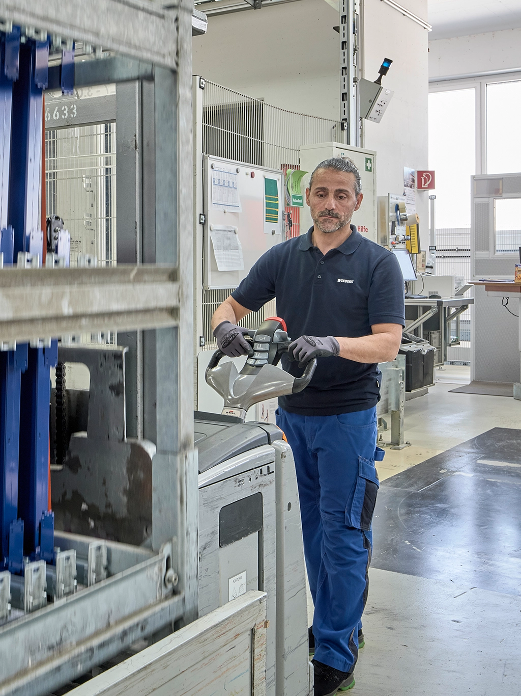 Fabrikarbeiter in Geberit-Arbeitskleidung bei der Arbeit in einer Produktionshalle.