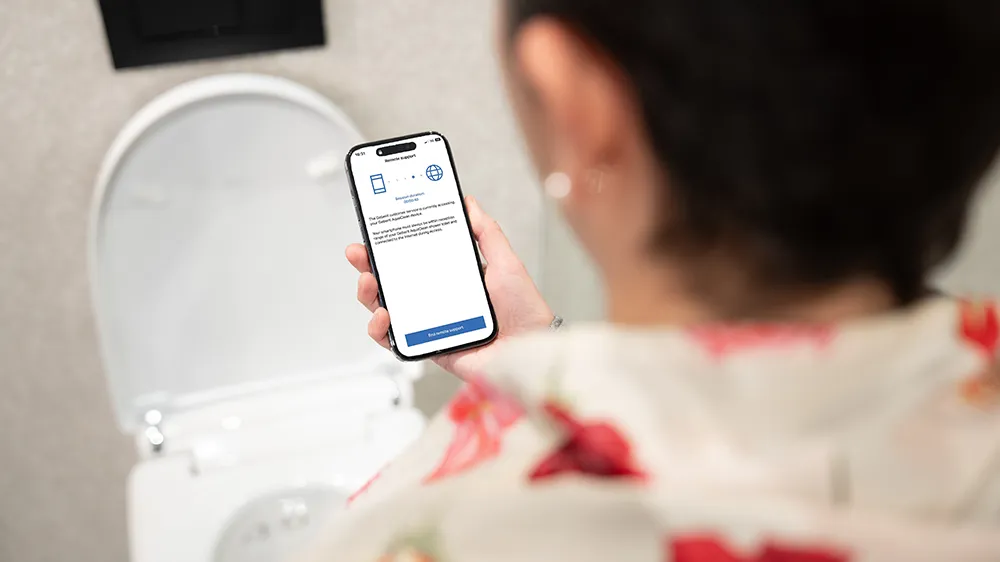 Eine Frau nutzt die Geberit Home App, mit der Benutzer Kundendienstmitarbeitern vorübergehend Zugriff auf ihre Duschtoilette gewähren können. (Foto)